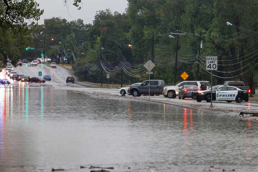 Oficiales de policía de Dallas bloquean el tráfico mientras el agua inunda la mayor parte de...