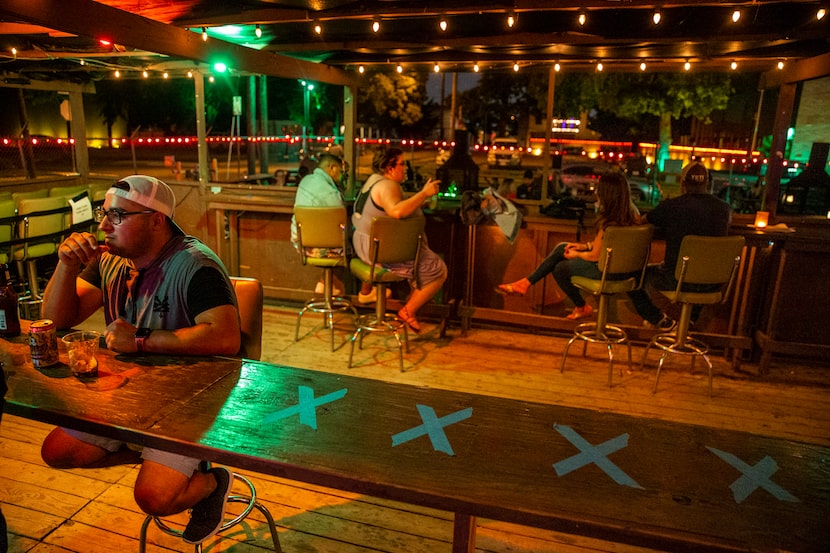 A row of taped 'X' letters demarcated social distancing guidelines as Martin Herrera (left)...