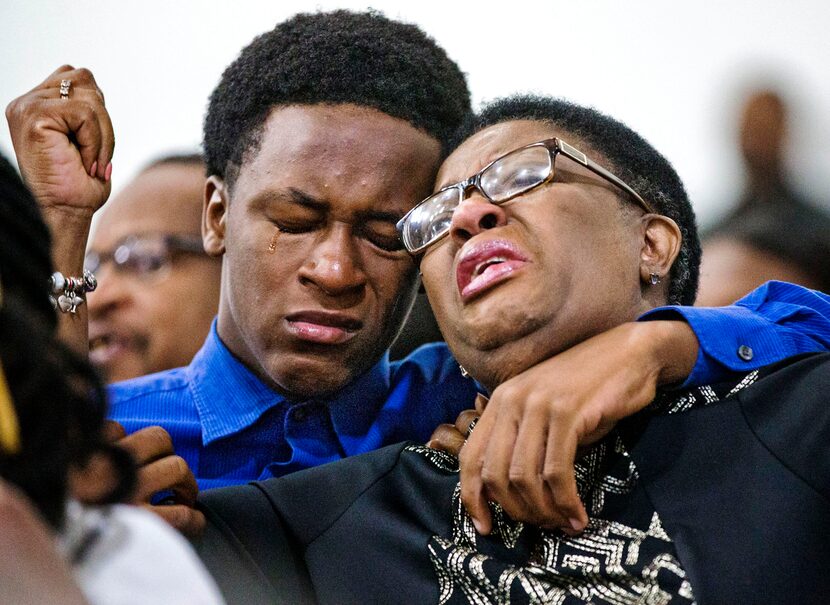 Allison Jean raises her hands in the air as she leans on her son, Brandt, 15, during a...