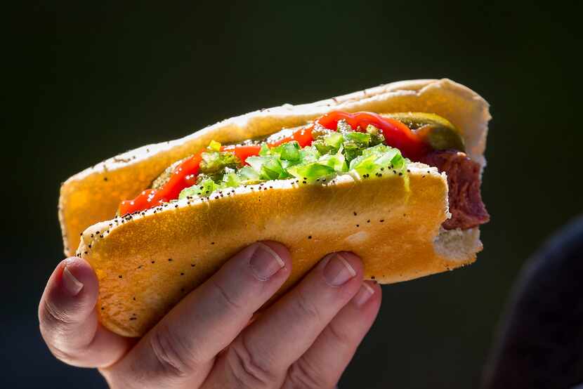 A fan eats a ballpark hot dog during a spring training baseball game between the Texas...