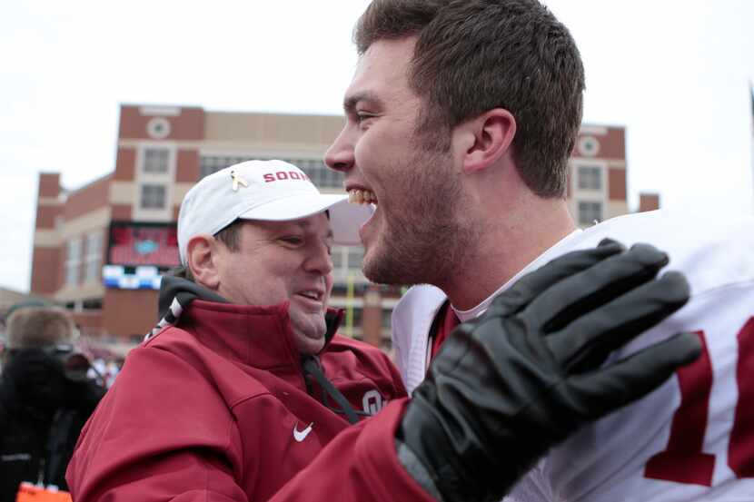 Quarterback Blake Bell hugs head coach Bob Stoops after the game against the Oklahoma State...