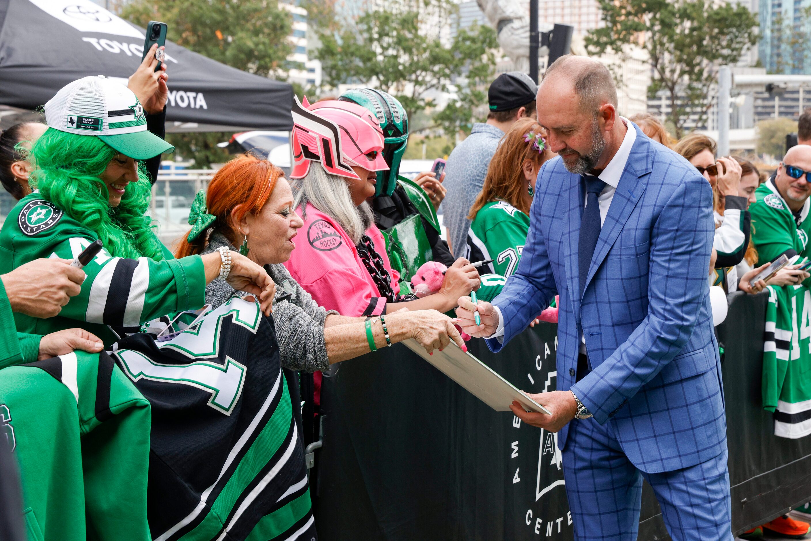 Dallas Stars head coach Peter DeBoer autographs a sign for a fan on the green carpet to the...