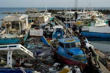 Fishermen push a boat damaged by Hurricane Beryl at the Bridgetown fisheries, Barbados,...