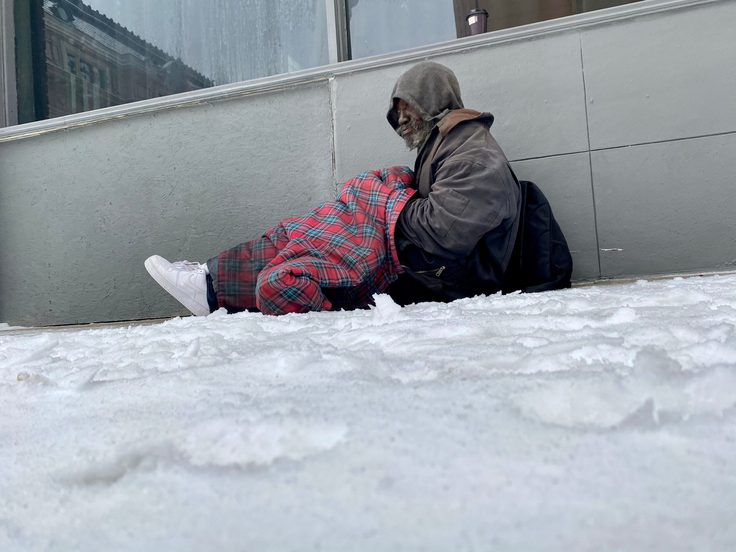 Darryl Davis sits on a grate to keep warm on Main Street early Wednesday morning February...