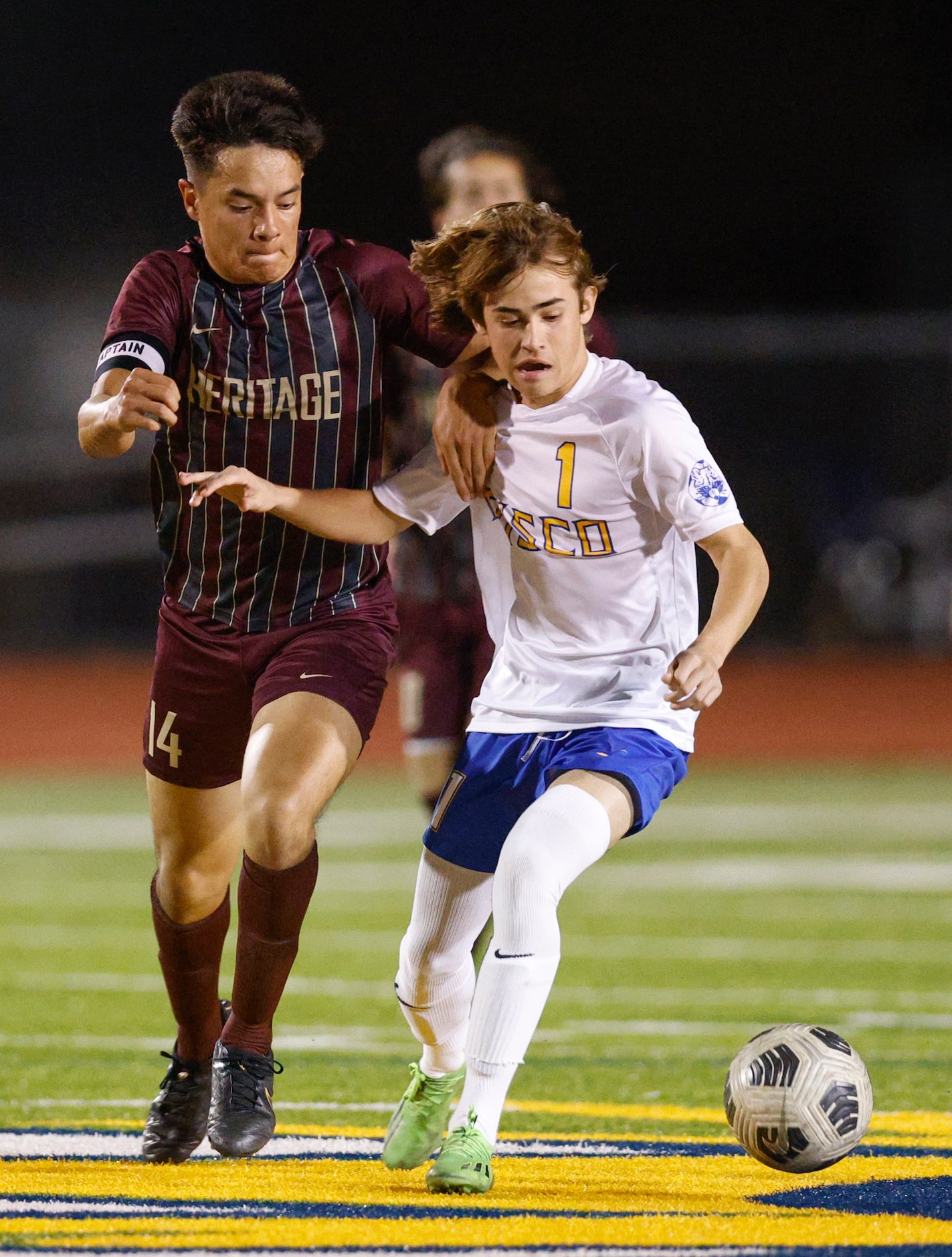 Frisco Heritage midfielder Chelo Pedraza (14) and Frisco’s Austin Lyman (1) battle for loose...