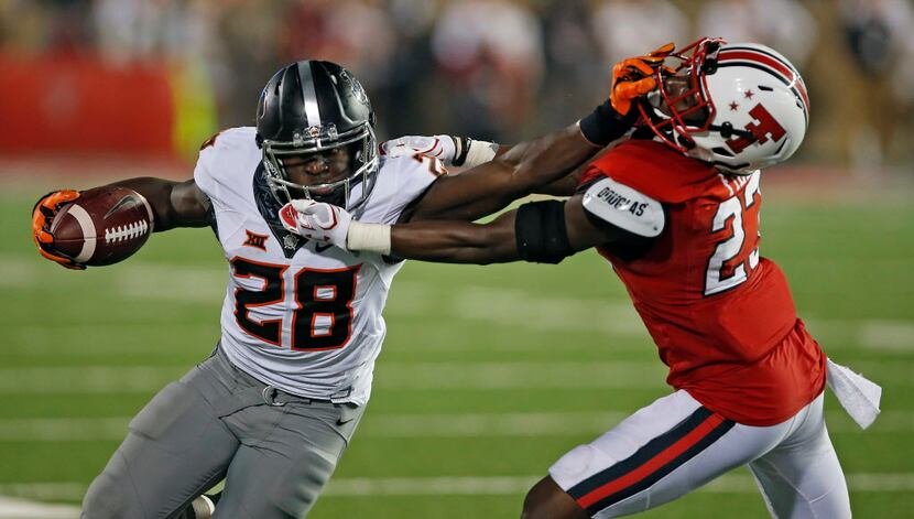 Oklahoma State's J.D. King (28) stiff arms Texas Tech's DaMarcus Fields (23) during an NCAA...