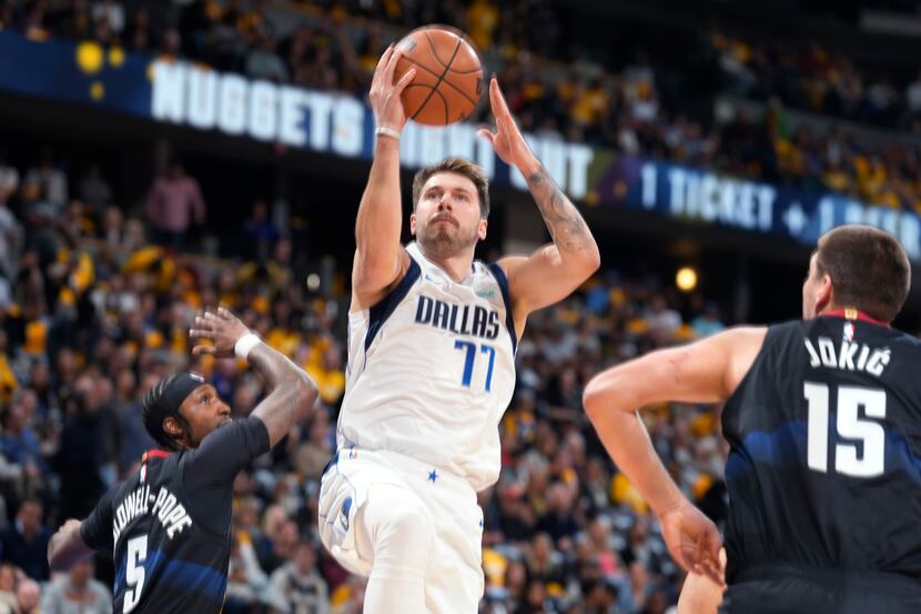 Dallas Mavericks guard Luka Doncic drives to the basket between Denver Nuggets guard...