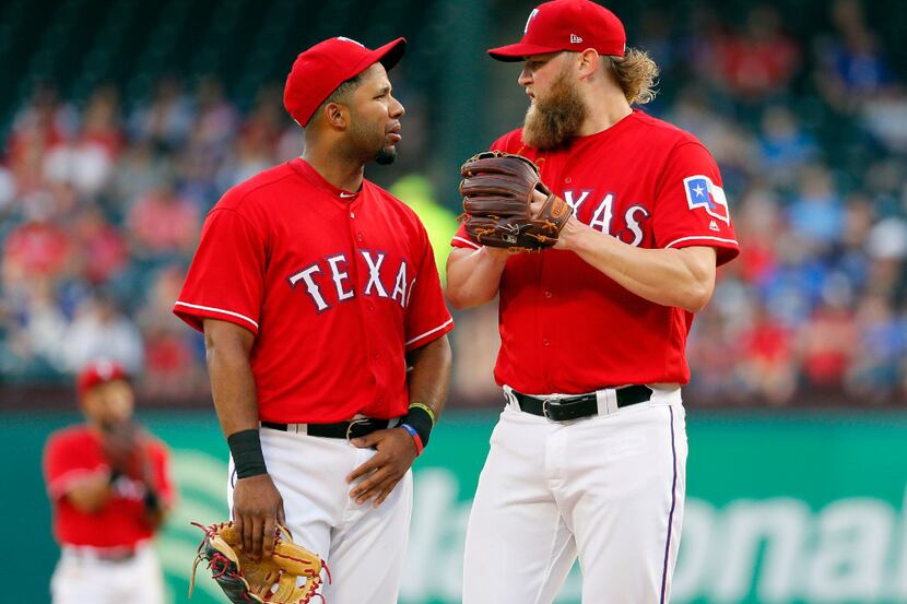 Texas Rangers' Elvis Andrus talks with starting pitcher Andrew Cashner, right, on the mound...