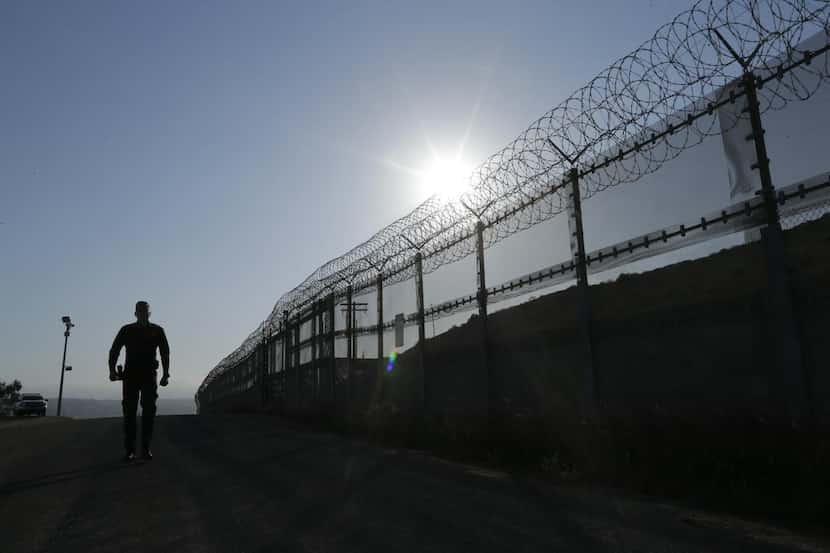 Un agente de la Patrulla Fronteriza camina por la valla de la frontera en San Diego,...