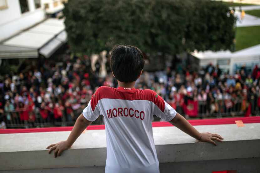 A child looks down from a balcony as fans celebrate during a homecoming parade of Morocco...