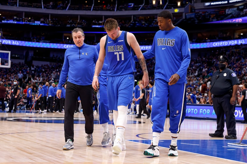 Dallas Mavericks guard Luka Doncic (77) limps off the court after injuring his lower left...