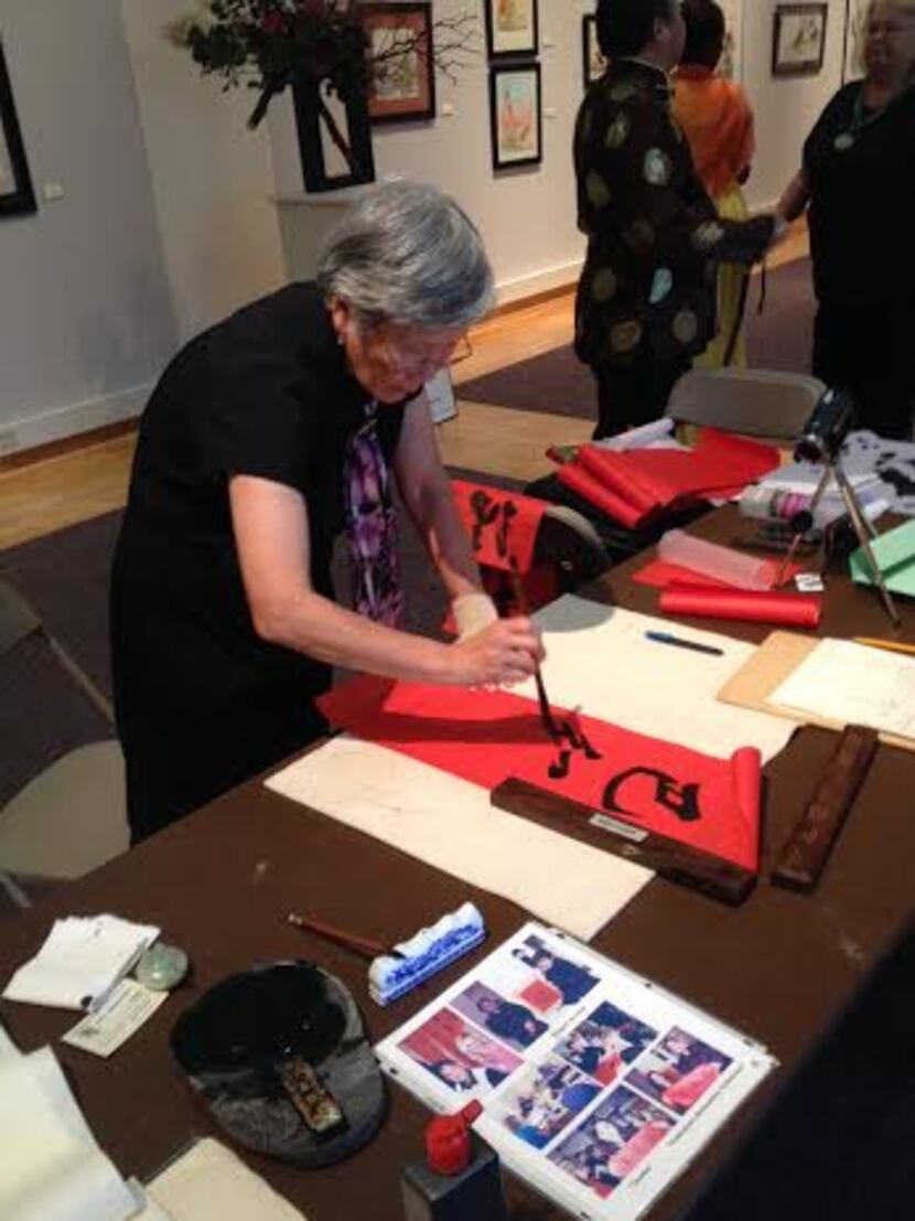
A woman demonstrates calligraphy at the opening reception for the East Meets West exhibit...