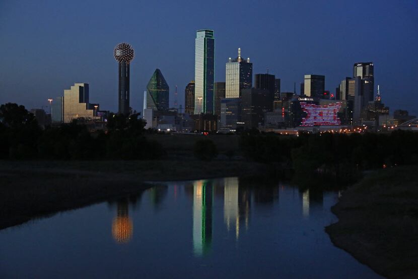 The sun sets, illuminating the Dallas skyline, as seen from  Trinity River Basin levee near...