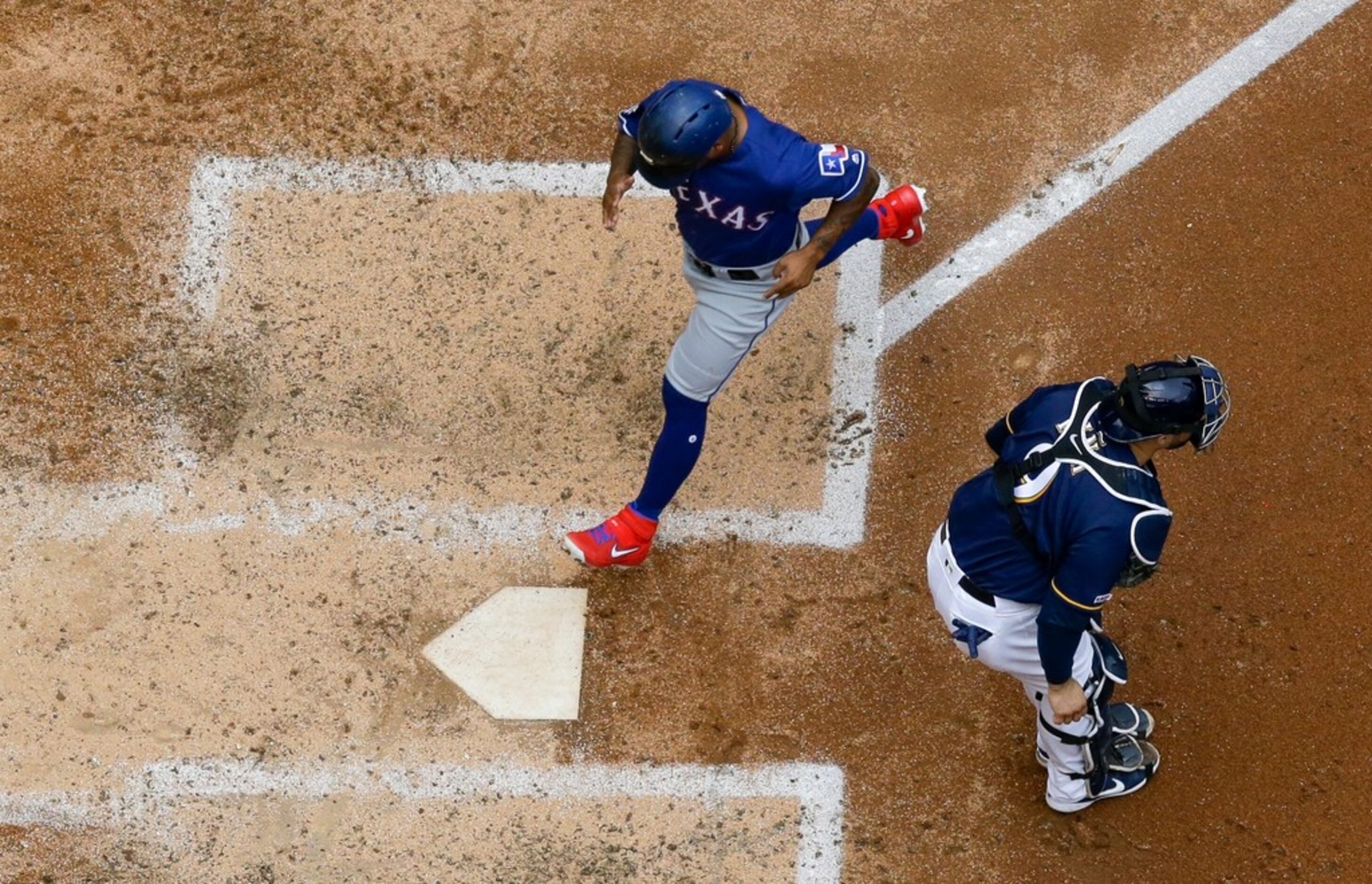 Texas Rangers' Delino DeShields scores past Milwaukee Brewers catcher Manny Pina during the...