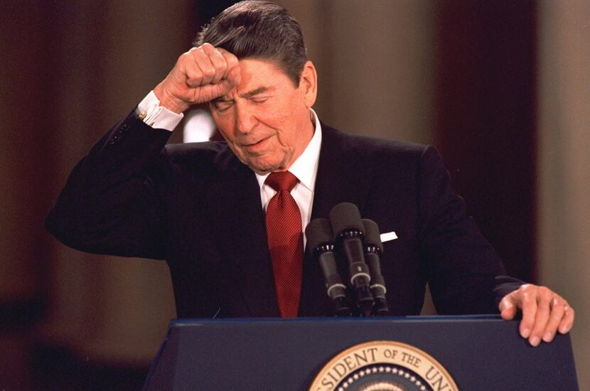 President Ronald Reagan taps his forehead at the White House while responding to a...