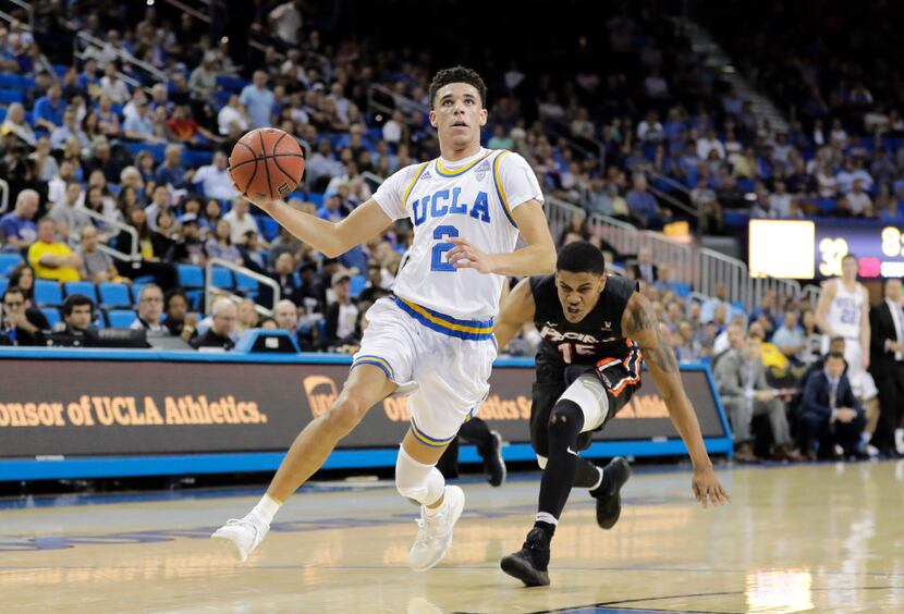 UCLA's Lonzo Ball, center, drives to the basket past Pacific's D.J. Ursery during the first...