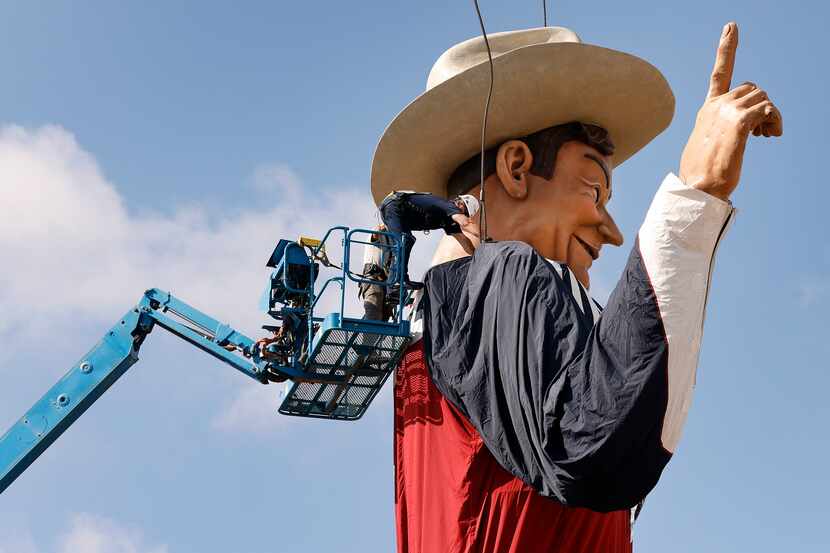 Los trabajadores sueltan las amarras utilizadas para levantar a Big Tex en el Big Tex Circle...