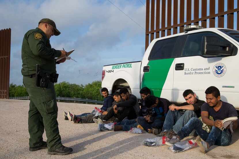 A Border Patrol agent apprehends immigrants entering the country illegally shortly after...