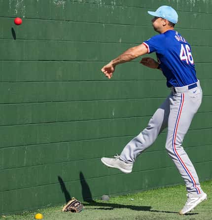 Texas Rangers pitcher Brock Burke tosses a heavy ball against a bullpen wall during a spring...