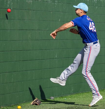 Texas Rangers pitcher Brock Burke tosses a heavy ball against a bullpen wall during a spring...