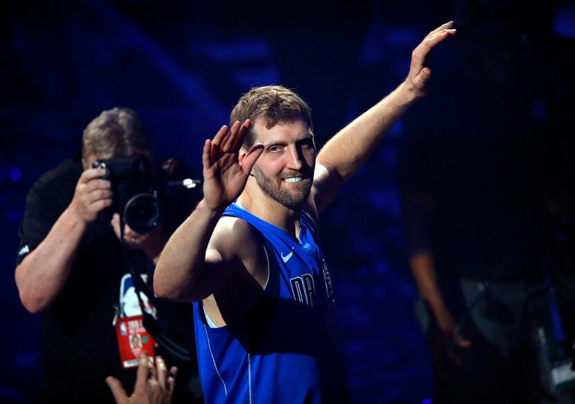 Dallas Mavericks forward Dirk Nowitzki waves to fans as he leaves the court following a...