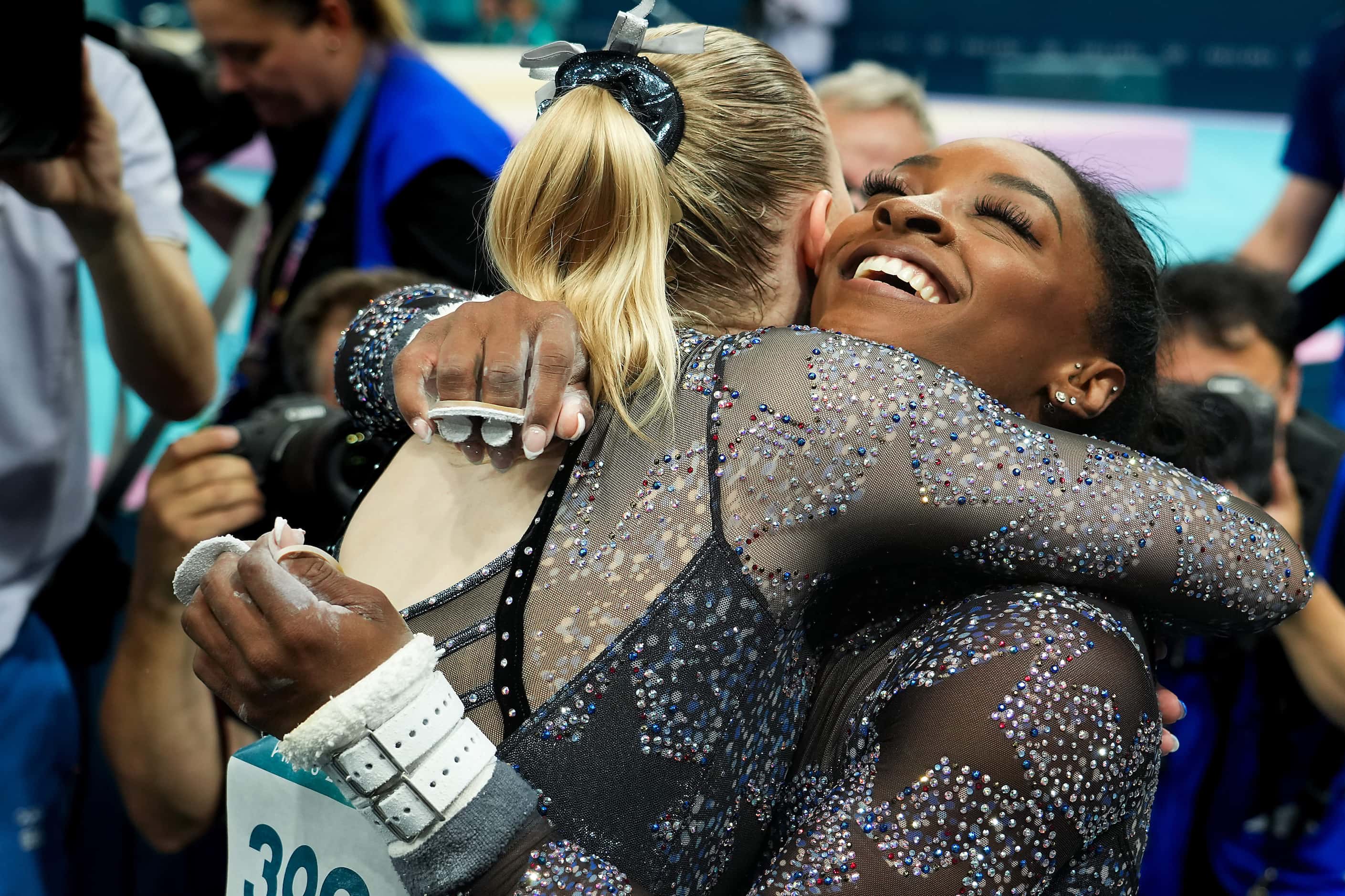 Simone Biles of the United States hugs teammate Jade Carey after competing on the uneven...