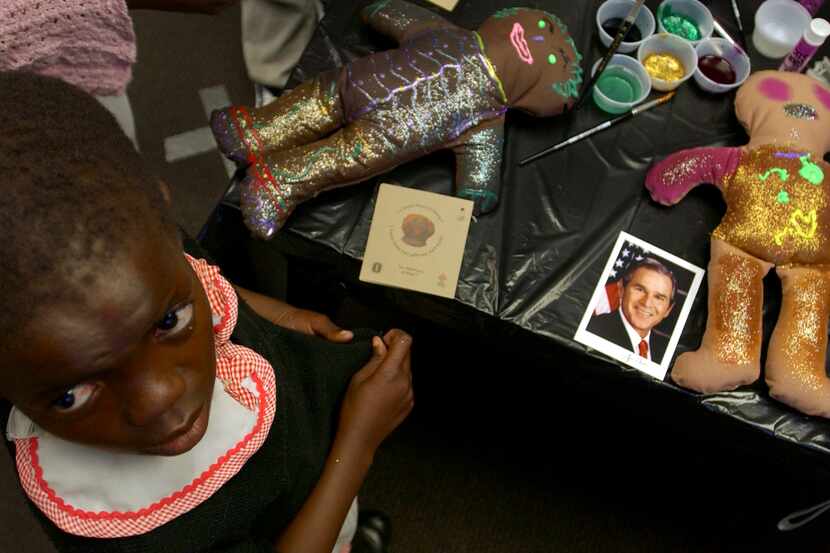 A child paints dolls as First Lady Laura Bush tours the Botswana-Baylor Children's Clinical...