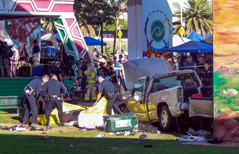 Police cover the bodies of people that were killed when a pickup landed on them after it...