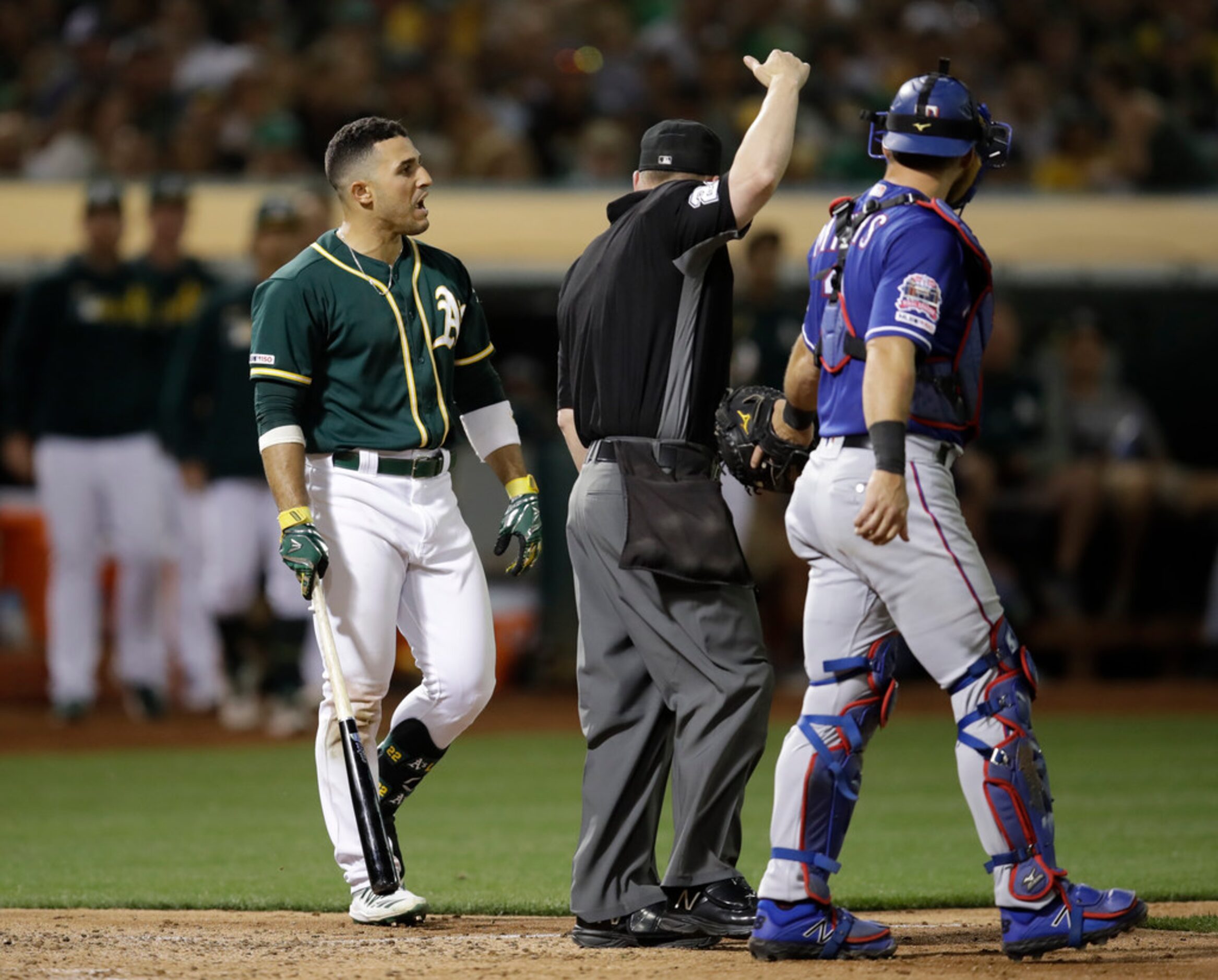 Oakland Athletics' Ramon Laureano, left, reacts after being hit by a pitch thrown by Texas...