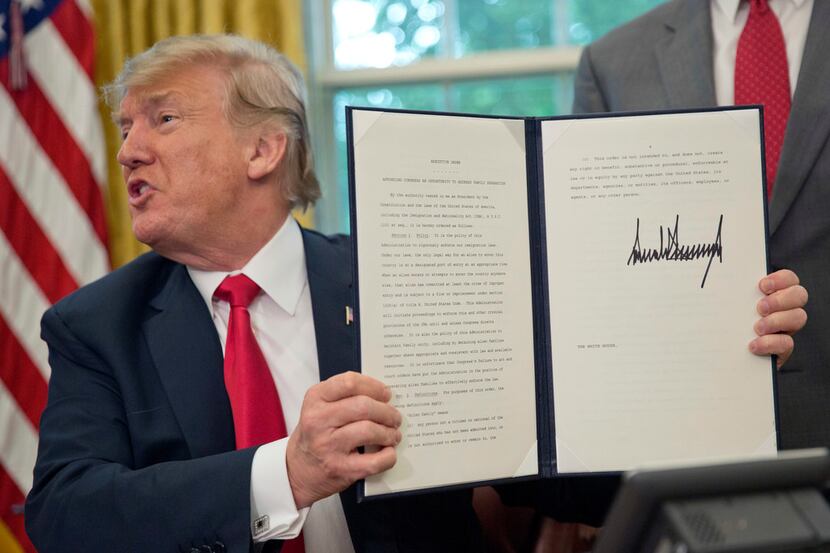 President Donald Trump holds up the executive order he signed to end family separations at...