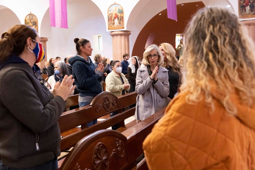 Myra Price (center in grey) offers other parishioners the sign of peace during mass at St....