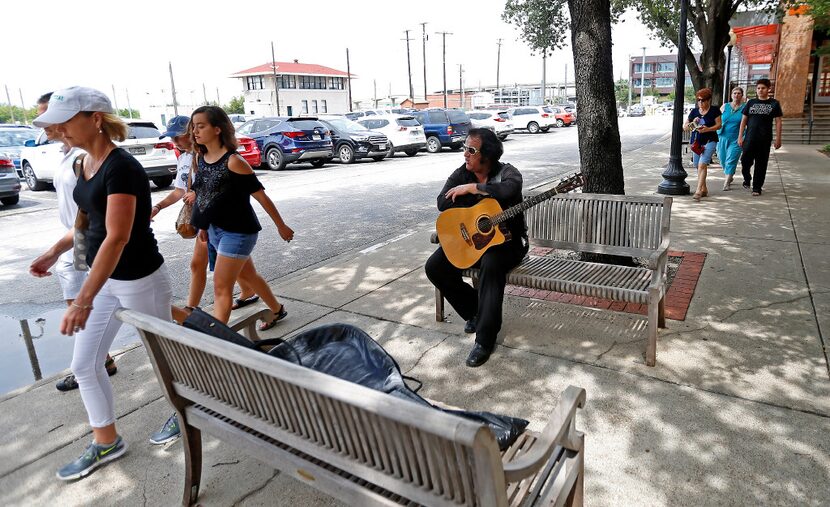 People walk by Elvis impersonator Phil Sneed near the entrance of Dallas County...