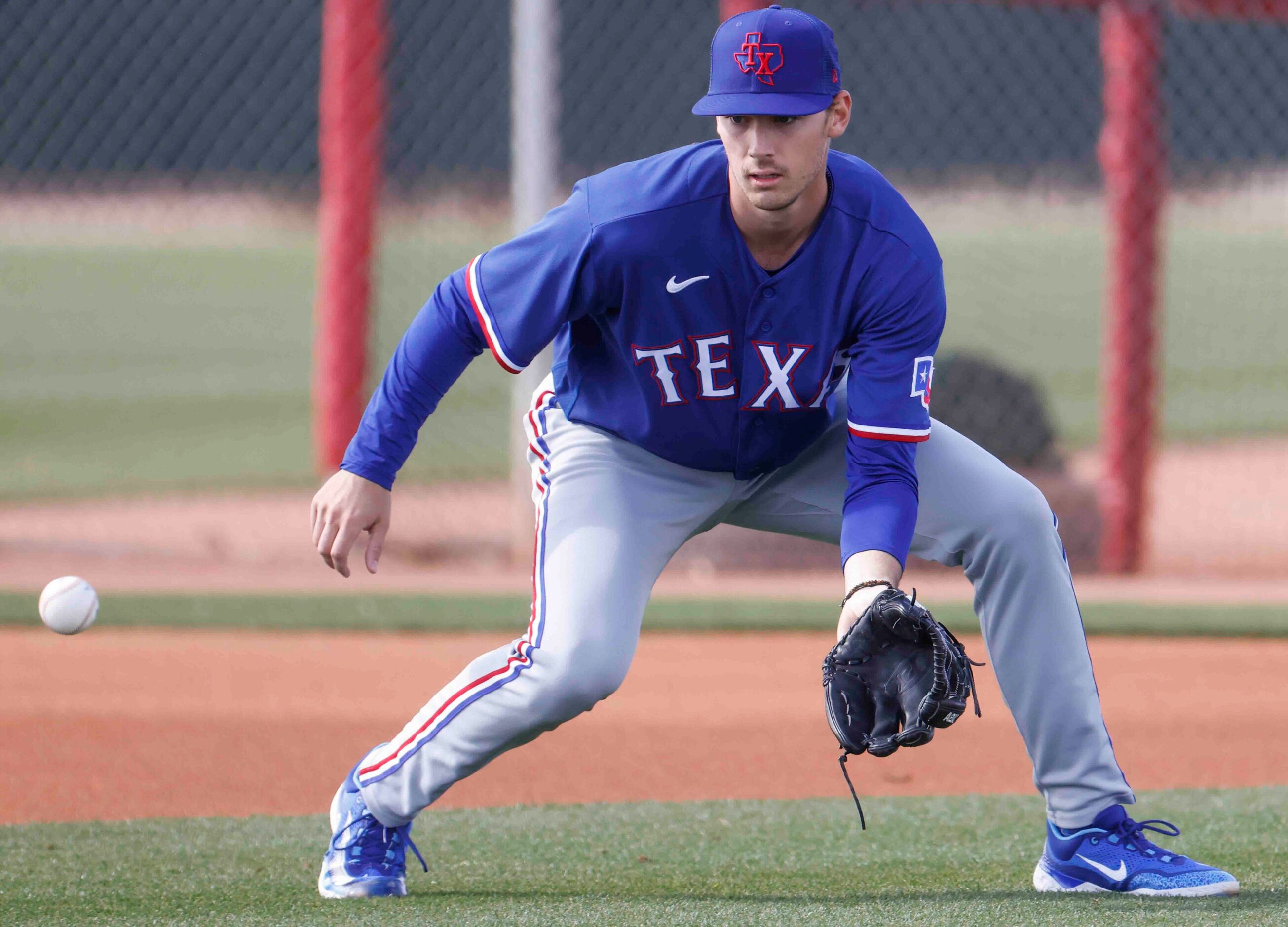 Texas Rangers pitcher Cole Winn fields the ball during a spring training workout at the...