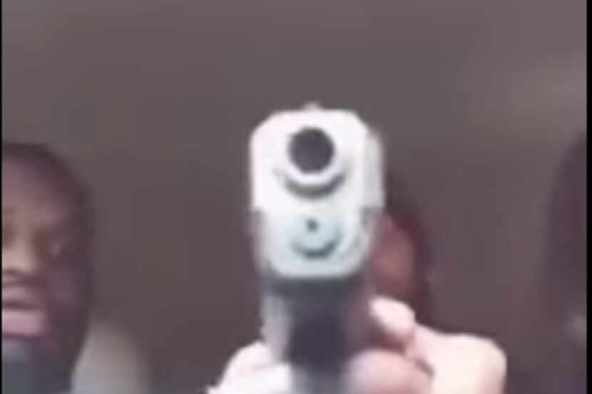 Devyn Holmes places his hand over Cassandra Damper's as she points a gun at the camera in a...