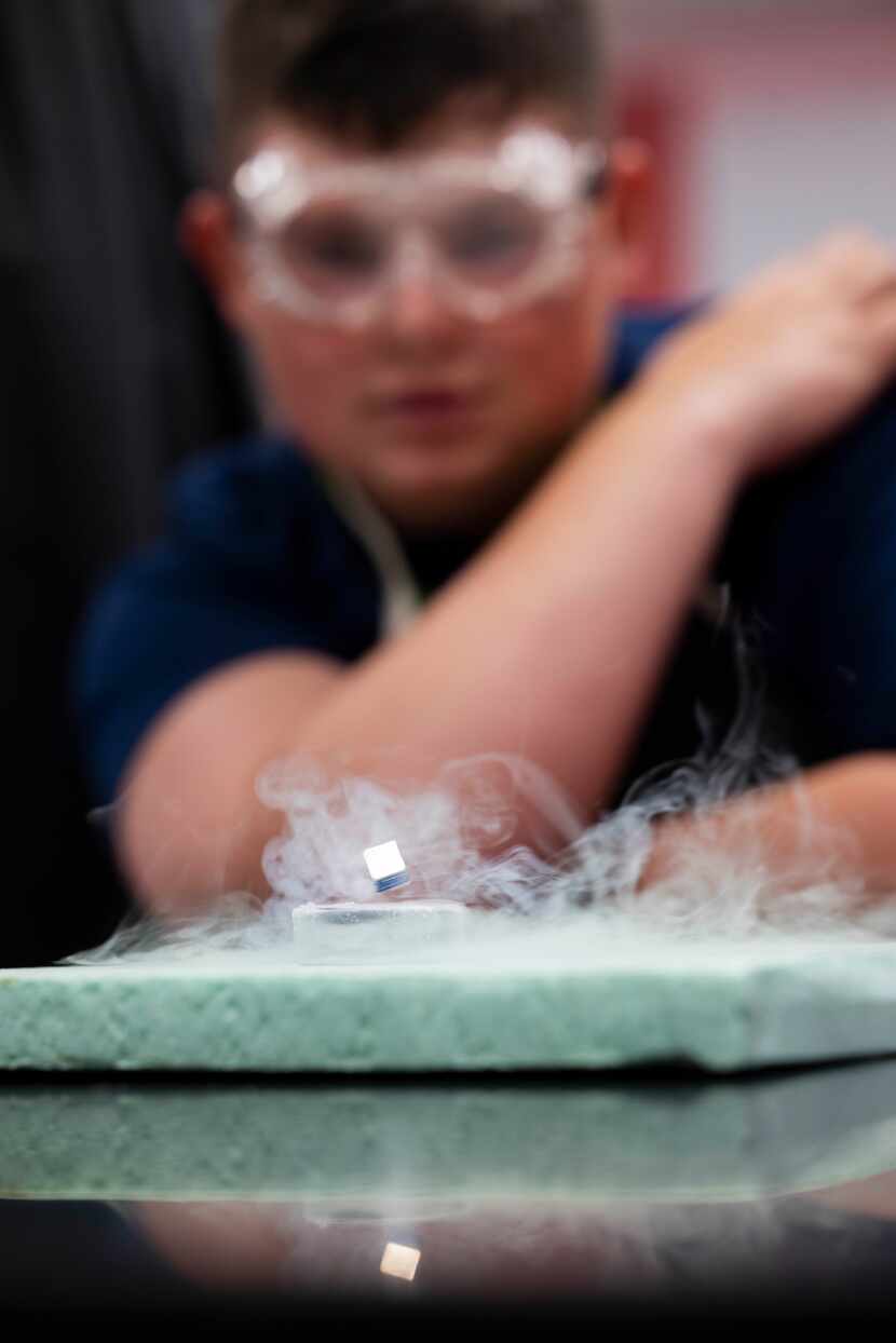 High school student Gavin Gilbreath Mann watches a magnet levitate over a superconductor...
