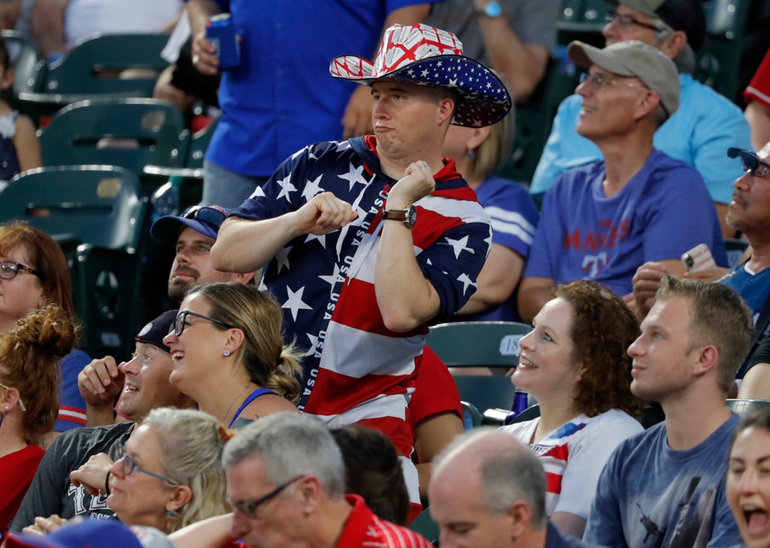 A fan dressed for the Fourth of July holiday dances to music in the stadium in the fifth...