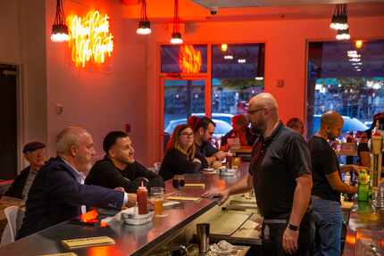 Owner Bryan Kaeser (right) visits with customers during the soft opening of Mudhook in...