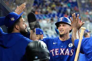 Texas Rangers' Corey Seager, right, is congratulated in the dugout after scoring on a single...