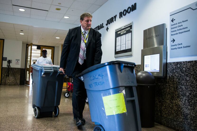 Large bins filled with questionnaires are wheeled out of the Central Jury Room after...