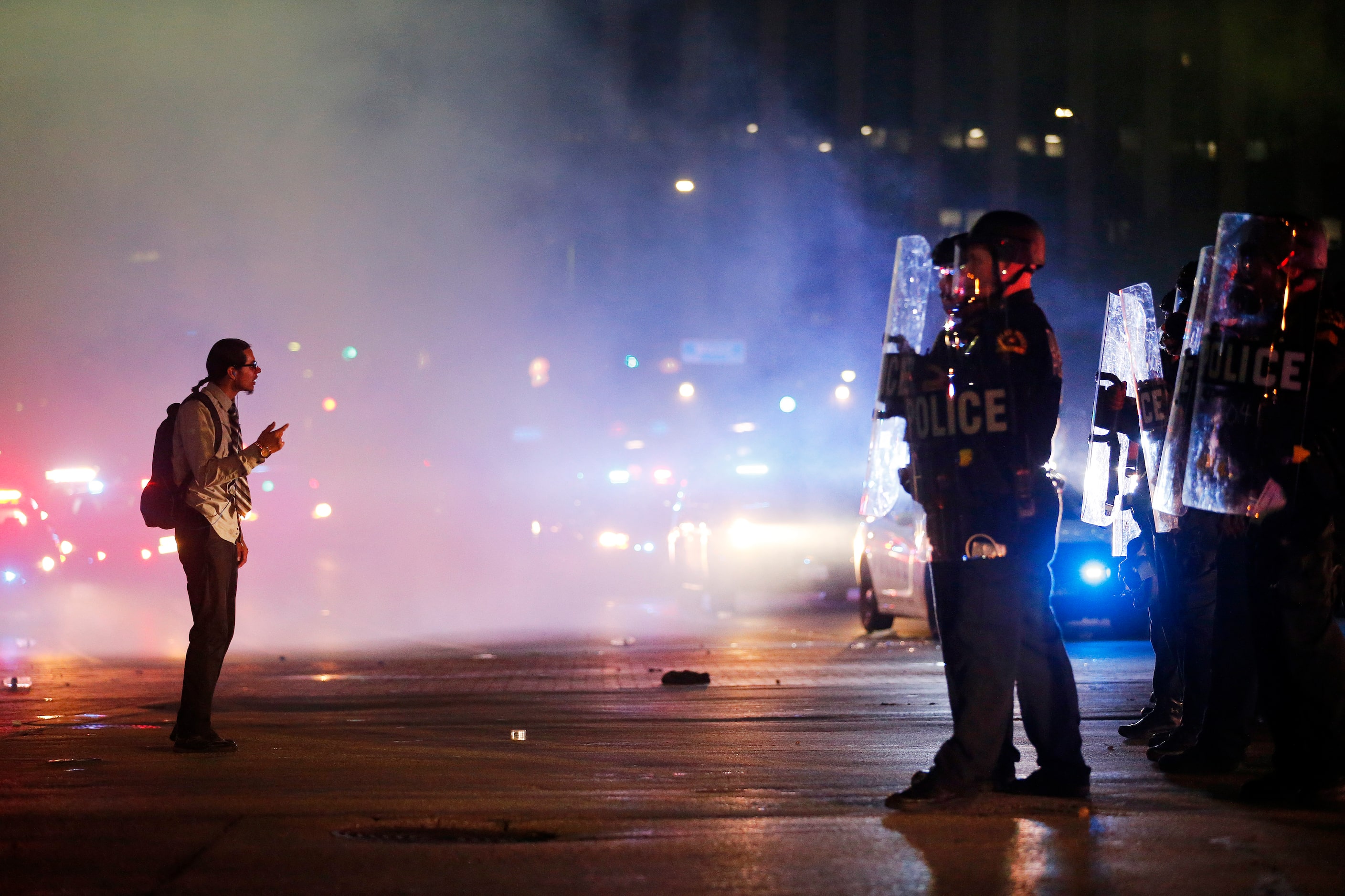 A protestor stands in the middle of the tear gas confronting tactical officers at the...