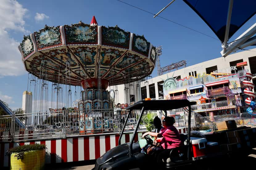 Workers ride a cart in preparation for the opening of the State Fair of Texas, Wednesday,...