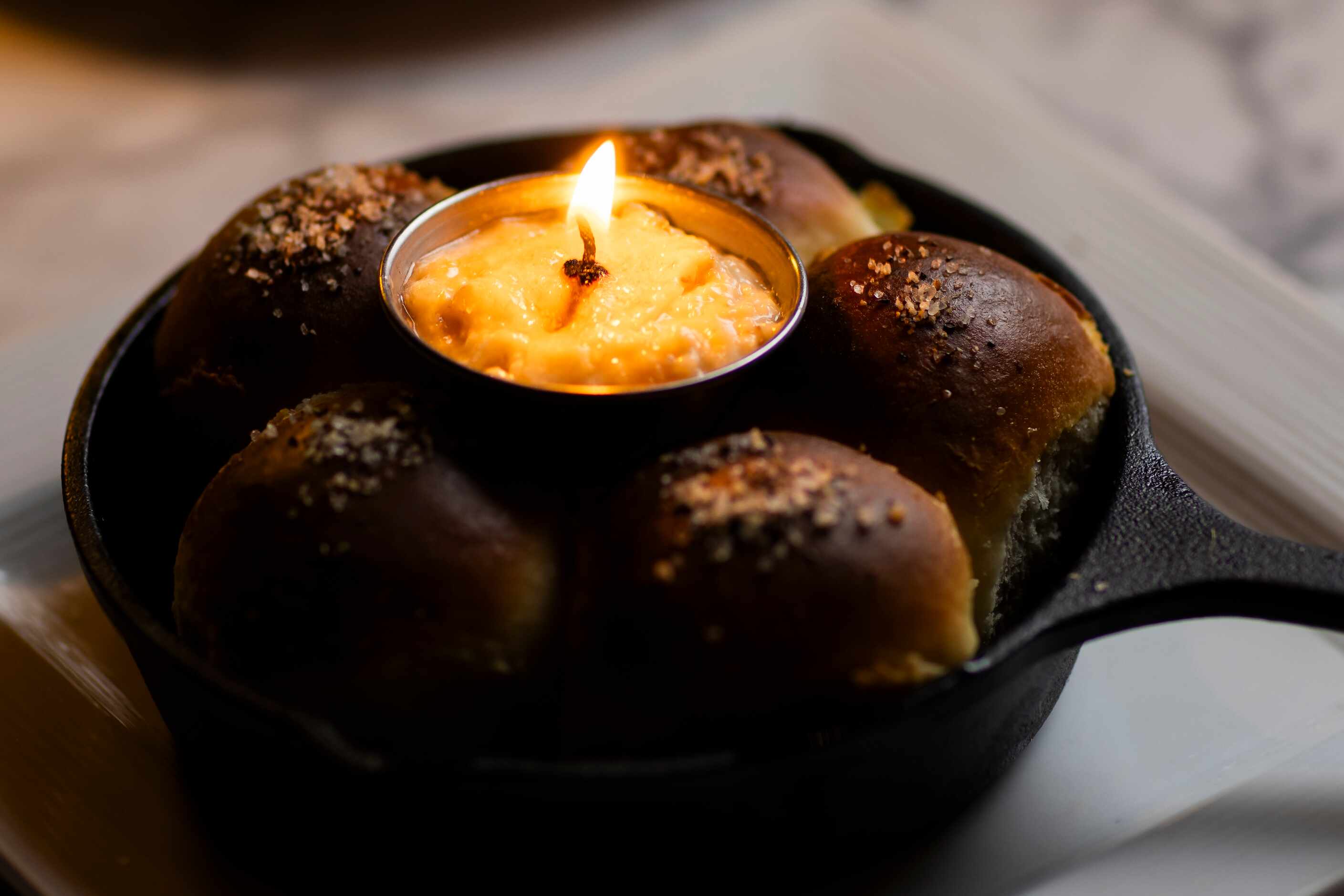 The Cast-Iron Parker House Rolls with smoked garlic salt and a roasted garlic butter candle...