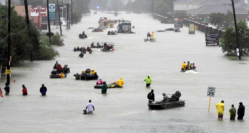 Rescue boats float on a flooded street as people are evacuated from rising floodwaters...
