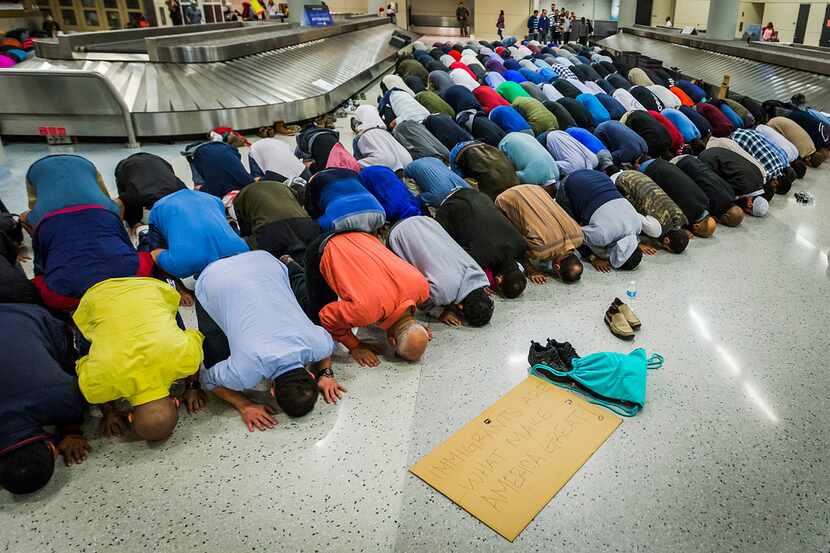 Muslim men set down their protest signs in January to pray at DFW International Airport,...
