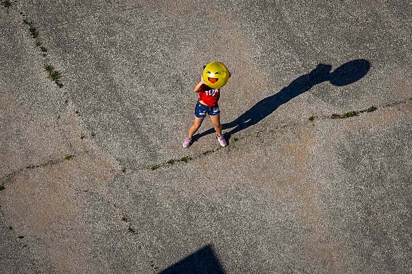 A child holds up a smiley face ball on a playground at D.A. Hulcy Middle School on Tuesday,...