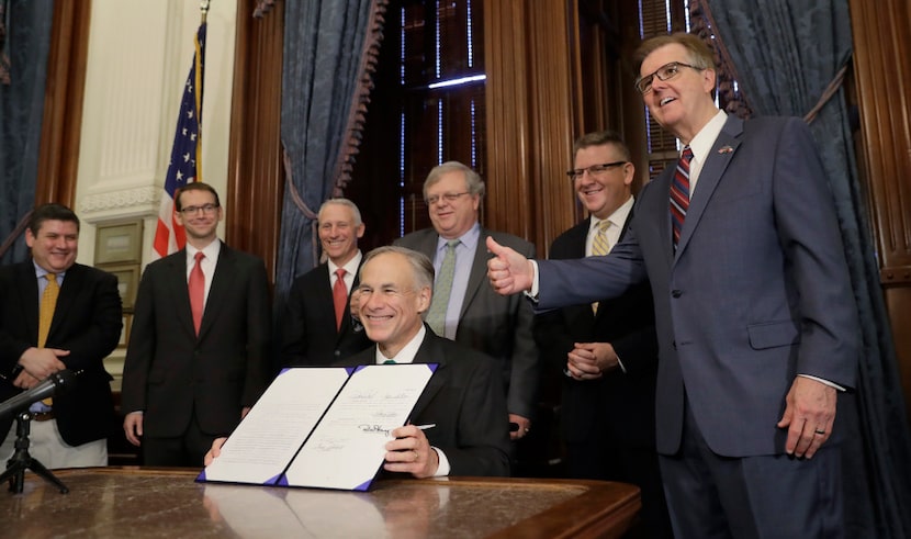 Texas Lt. Gov. Dan Patrick, right, gives a thumbs up sign as Gov. Greg Abbott, center, holds...