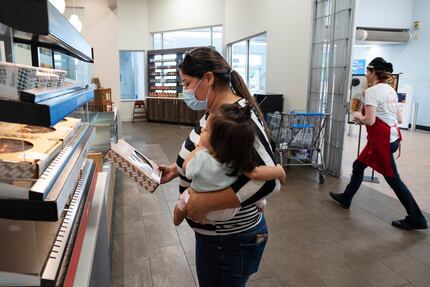 Zaira Garcia holds her baby Liliana Garcia as she picks up a grab-and-go pizza from La...