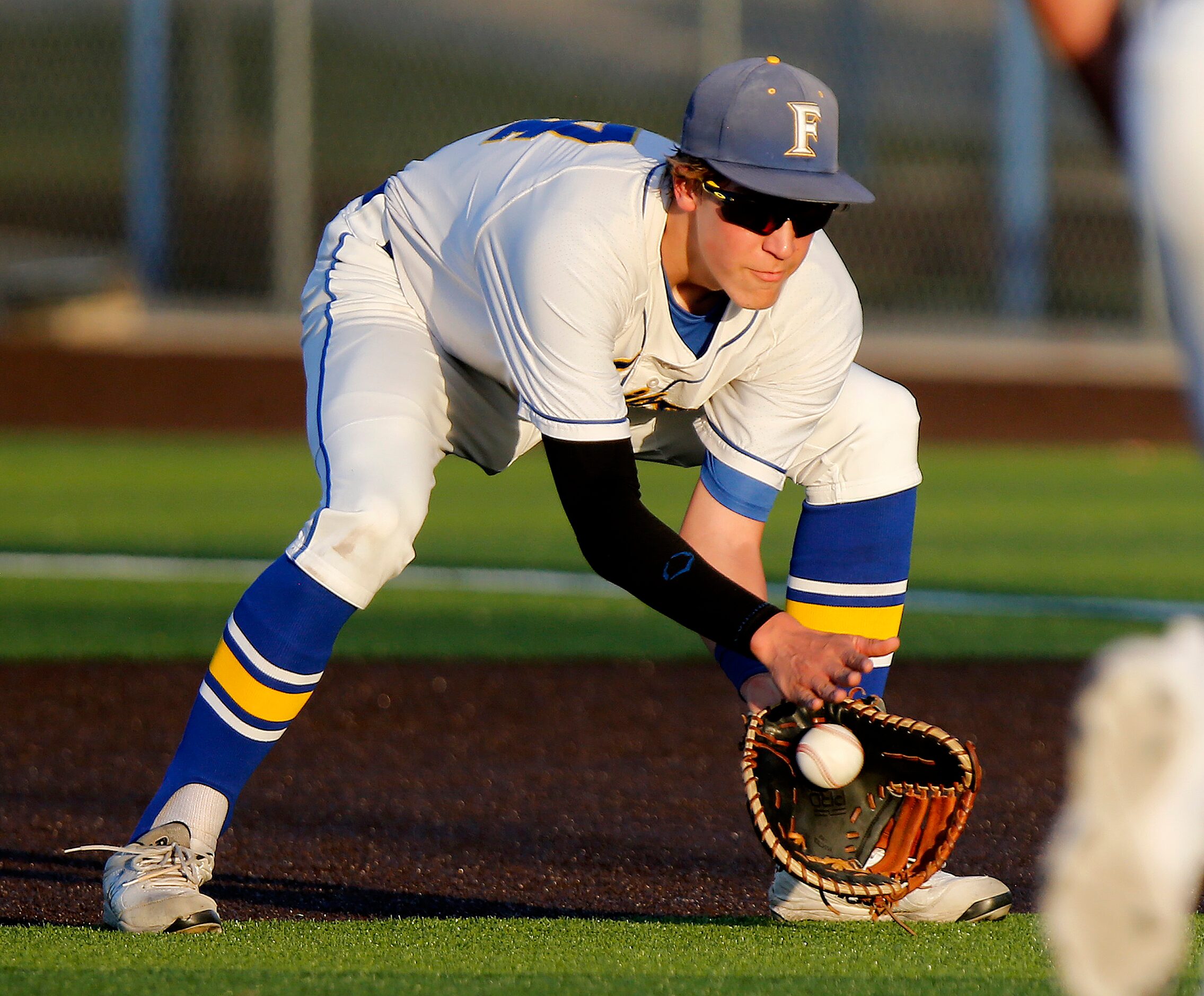 Frisco first baseman John Larkin (14) fields a grounder and takes it to first base himself...