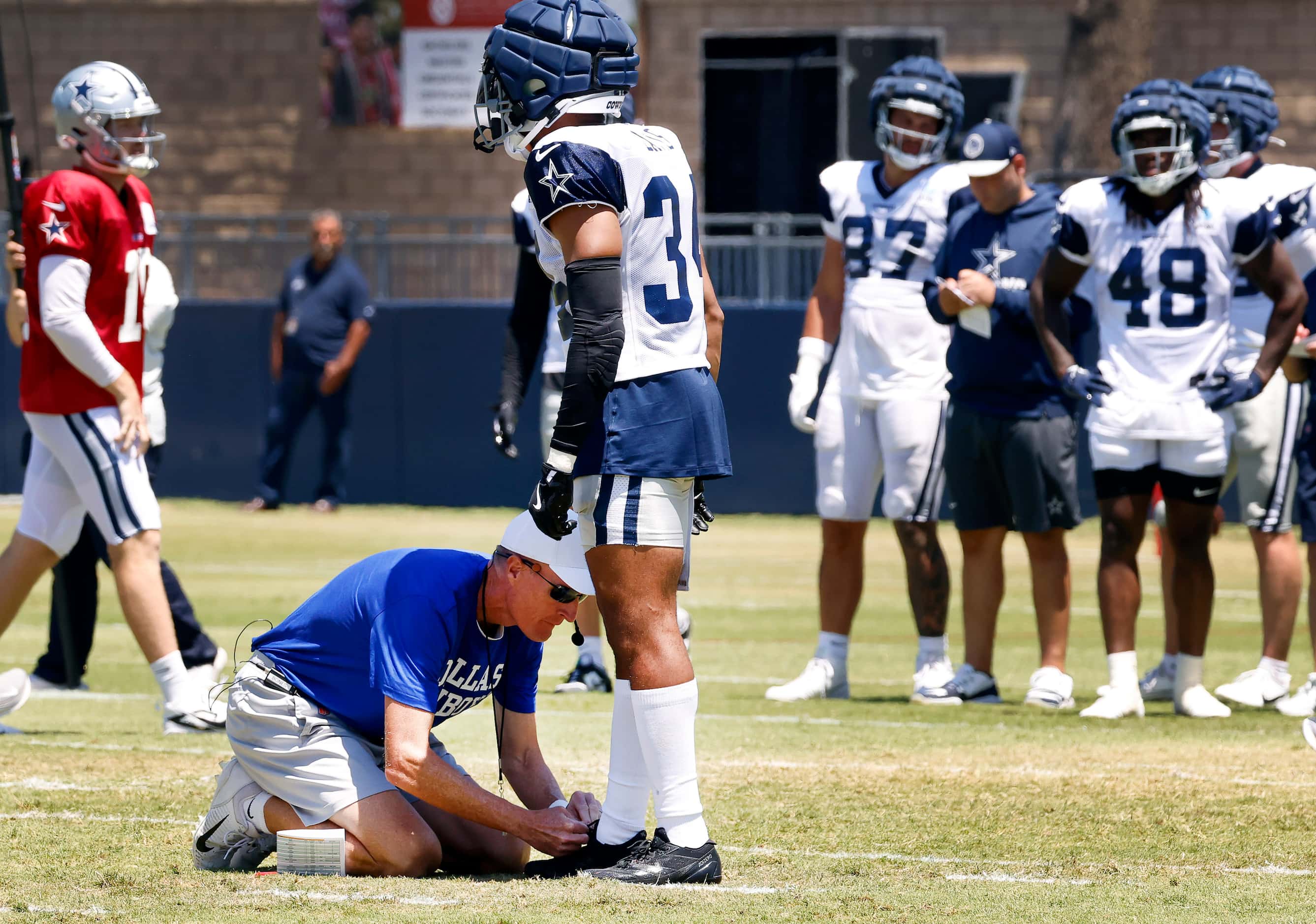Dallas Cowboys special teams coach John Fossel ties running back Malik Davis’ shoes between...