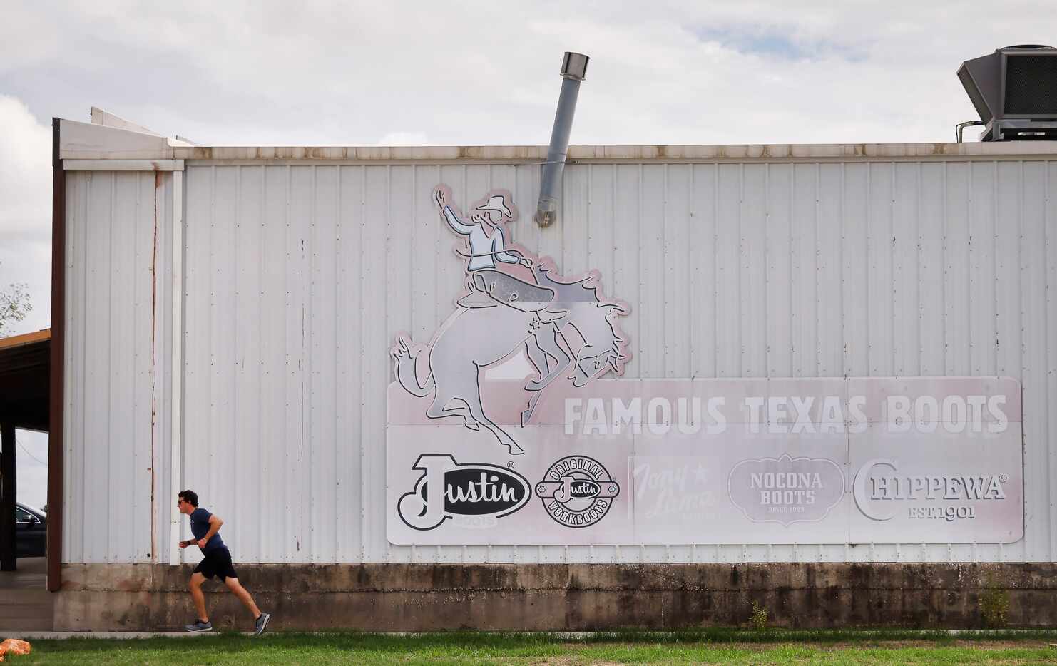 A man runs past the Justin Discount Boots Warehouse along FM 156 in Justin on Aug. 23.